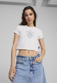 Hvid cropped t-shirt med korte ærmer og et grafisk tryk i blå på fronten, parret med en lyseblå denimnederdel.
