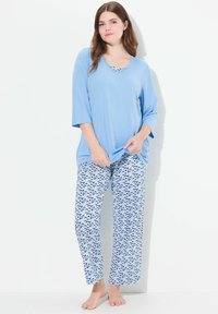 Lichtblauwe top met korte mouwen en een V-hals; losse, patronen broek in blauw en witte golven. Zachte stof, comfortabel ontwerp.