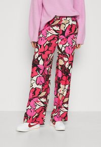 Flöda, vida byxor med ett livligt blommönster i rosa, svart och beige. Den elastiska midjebandet möjliggör komfort och lätthet.