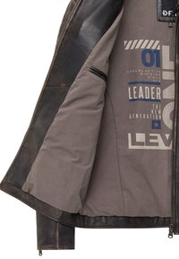 Interieur van een bruin leren jack met een grijze stof met bedrukte afbeeldingen in blauw en wit. Inclusief een ritszak aan de linkerkant.