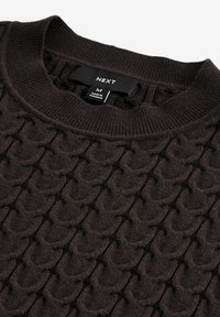 Ciemnobrązowy sweter dzianinowy z fakturowanym, wypukłym wzorem. Posiada okrągły dekolt oraz metkę wskazującą rozmiar M.