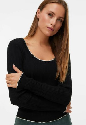 Black ribbed sweater with a scoop neckline and contrasting white bead trim along the edges and sleeves. Fitted design with long sleeves.