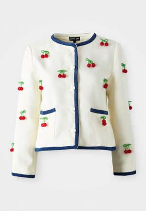 Veste blanche en texture avec des bordures bleues, boutons sur le devant, deux poches et des embellissements en cerise perlée rouge dispersés sur les manches et le devant.