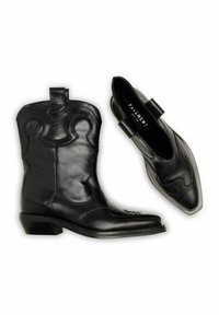 Mustade nahast saapad Läänes stiilis õmblustega ja madalate kontsadega, üks saabas on püsti ja teine vaadatakse ülevalt.