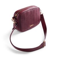 Burgundy crossbody bag with a woven texture, gold hardware, and a flat design. Features a removable strap and zip closure.