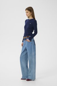 Navy ribbed long-sleeve shirt paired with loose light blue denim wide-leg jeans and brown belt, featuring side pockets and minimal detailing.