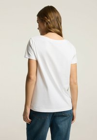 Biała, krótki rękaw, t-shirt wykonany z miękkiej bawełny. Posiada lekko zaokrąglony dekolt, luźny krój i gładką strukturę.