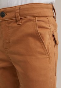 Tan katoen broek met een gladde textuur, voorzien van gestikte zijzakken en een knoopsluiting bij de taille.