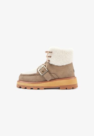 Bottines en daim marron avec un revers en sherpa crème duveteux, dotées d'une boucle sur le côté et d'une semelle en caoutchouc texturé et robuste.