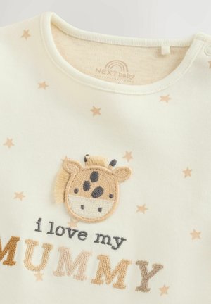 Chemise à manches longues crème avec des étoiles beiges, présentant une applique de girafe texturée et l'inscription brodée "J'aime ma MAMAN" en couleurs variées.