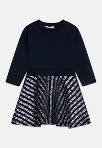 Marineblauw langetermijnoverhemd met een effen bovenkant en een uitlopende rok, versierd met een witte geometrische kettinglinkpatroon.