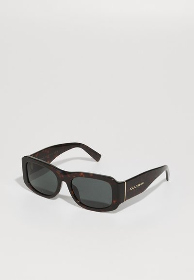 Gafas de sol de carey marrón con montura cuadrada, lentes oscuros y detalles en dorado en las patillas que presentan el nombre de la marca grabado.