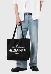 Borsa a tracolla nera in tela con grande testo bianco "ALLSAINTS LONDON" e design "Infinite Summer". Presenta due manici e un ampio interno.
