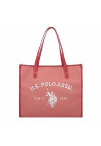Röd canvas tote-väska med dubbla handtag, med vit U.S. Polo Assn. logotyp och etableringsdatum. Kontrastsydda sömmar och metallaccenter.