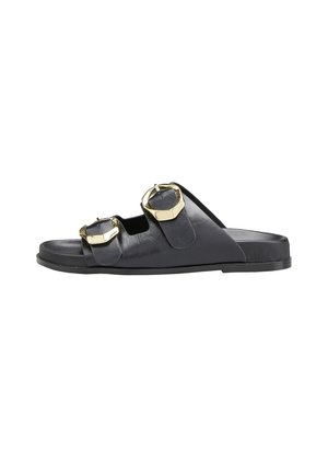 Sandale à enfiler en cuir noir avec deux sangles ajustables munies de boucles dorées, semelle plate et design ouvert pour la ventilation.