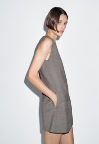 Grau Leinenkleid mit ärmellosem Design, Seitentaschen und gerader Silhouette. Glatte Textur mit einem dezenten Muster.