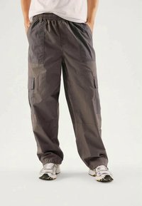Gray cargo pants made of lightweight fabric with an elastic waistband, featuring multiple side pockets and a loose fit for comfort.