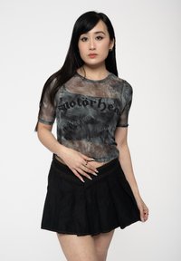 Sheer gray mesh t-shirt with black "motorhead" text, paired with a black pleated skirt. The top has a round neckline and short sleeves.