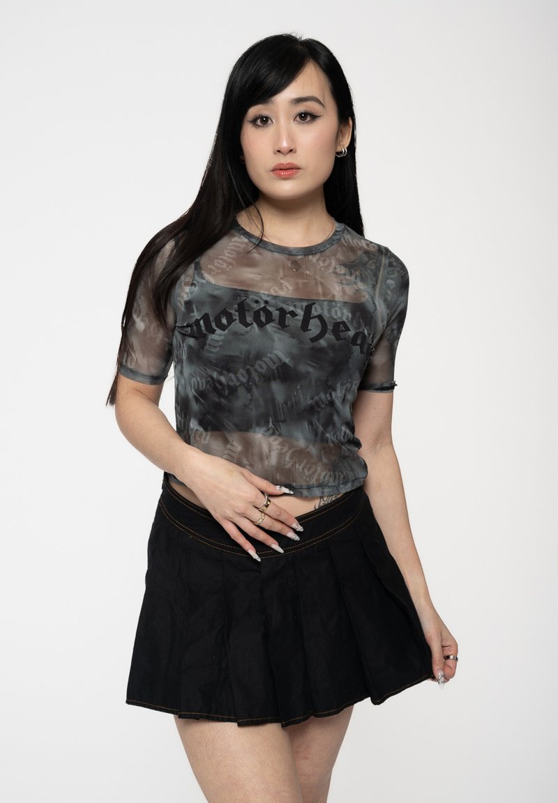 Sheer gray mesh t-shirt with black "motorhead" text, paired with a black pleated skirt. The top has a round neckline and short sleeves.