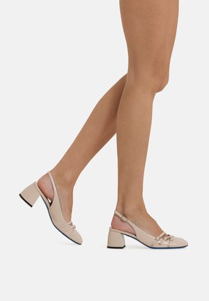 Beige Slingback-Absatzschuhe mit glänzender Oberfläche, breitem Blockabsatz, mehreren Riemen auf der Vorderseite und einem kleinen Schnallen-Detail am Knöchelriemen.