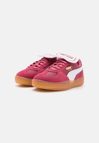 Røde ruskindsneakers med hvide læderdetaljer og gummisåler. Har en polstret tunge med logo og snørremekanik.