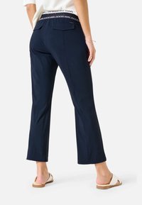 Námořnicky modré krátké kalhoty s hladkou texturou, vybavené plochým pasem, dvěma zadními kapsami a rovnými nohavicemi.