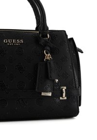 Borsa in pelle sintetica nera con motivi a rilievo, manici doppi, hardware dorato e un'etichetta con il nome del marchio. Chiusura superiore con zip.