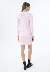 Roosa kootud kleit, millel on nöörmustrid, pikad varrukad, sobiv siluett ja soonikkoesäär. Kombineeritud mustade pahkluu saapadega.