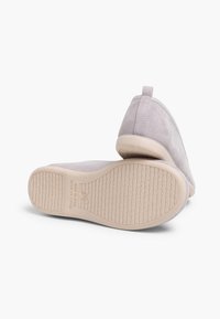 Zapatos de ante gris claro con puntera redondeada, tacón bajo y suela de goma texturizada. Presentan una lengüeta trasera para ponerlos y quitarlos fácilmente.