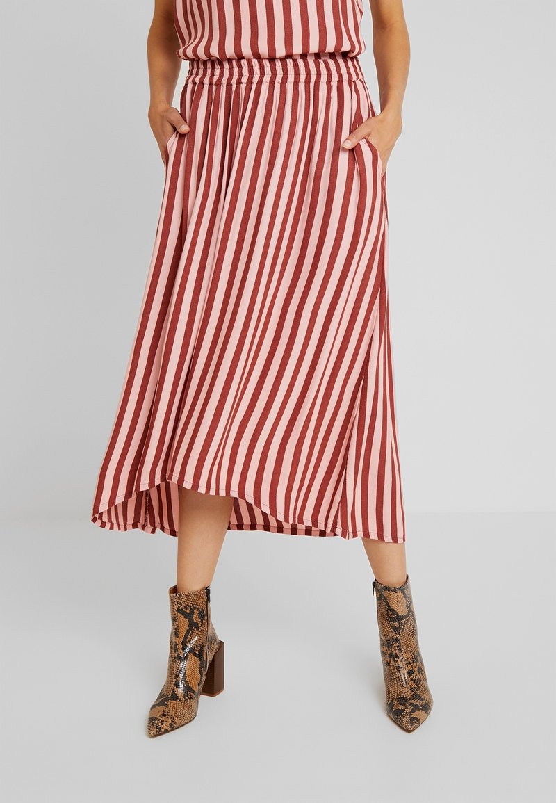 Falda midi a rayas rojas y rosas con cinturilla elástica y bolsillos laterales, combinada con botas de tobillo de estampado de serpiente marrón.