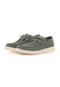 Zapatos de lona verde oliva con suelas de goma beige claro, punta redonda y cordones trenzados. Con un detalle de cuero marrón en el talón.