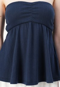Navy blue strapless top made of textured fabric with vertical ribbing, featuring a gathered bodice and a flared, loose silhouette.