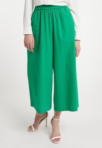Groene wijde pantalons met een elastische taille, gemaakt van lichtgewicht stof. Heeft een gladde textuur en een losse, vloeiende pasvorm.