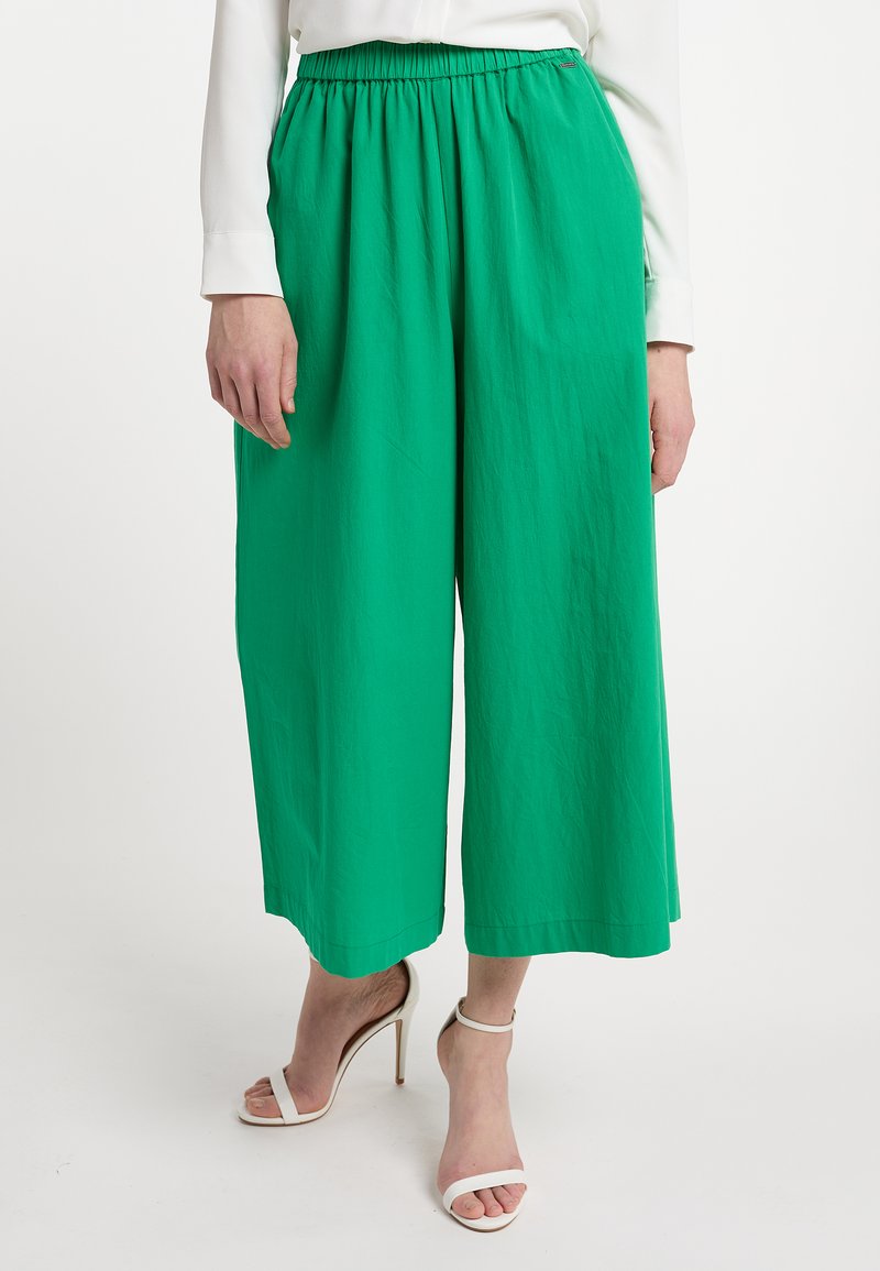 Groene wijde pantalons met een elastische taille, gemaakt van lichtgewicht stof. Heeft een gladde textuur en een losse, vloeiende pasvorm.