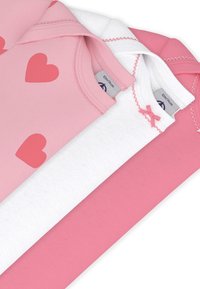 Τρία βαμβακερά βρεφικά ενδύματα: ένα ροζ με σχέδια καρδιών, ένα λευκό απλό με ροζ φιόγκο, και ένα άλλο απλό ροζ.