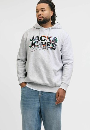 Sudadera gris con un estampado de logo multicolor que dice "JACK & JONES Essentials". Puños y dobladillo acanalados, combinada con jeans de un azul claro.