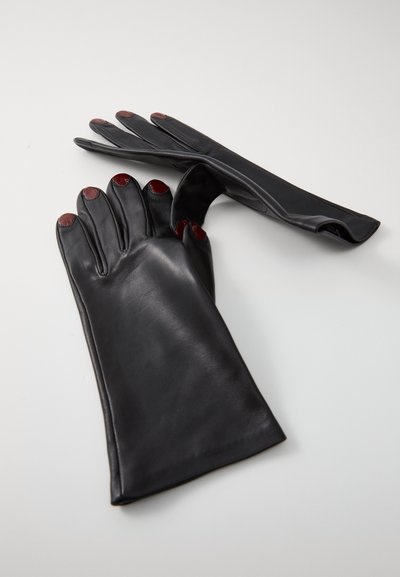 Gants en cuir noir avec une finition lisse, présentant des accents rouges sur les bouts des doigts et un design ajusté. Les gants sont à doigts et élégants.