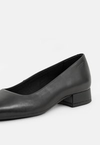 Černá kožená bota na plochém podrážce s kulatou špičkou a nízkým blokovým podpatkem. Hladká textura s jednoduchým designem bez viditelných ozdob.