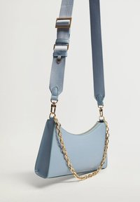 Borsa a spalla azzurra chiara con finitura texturizzata, caratterizzata da un accento in catena dorata e una tracolla staccabile con fibbia regolabile.