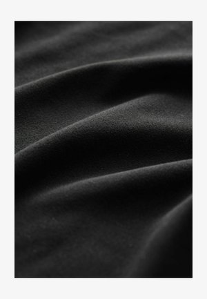 Tessuto nero con una superficie liscia e leggermente strutturata, drappeggiato in morbide pieghe, che mette in risalto la sua qualità premium e il colore uniforme.