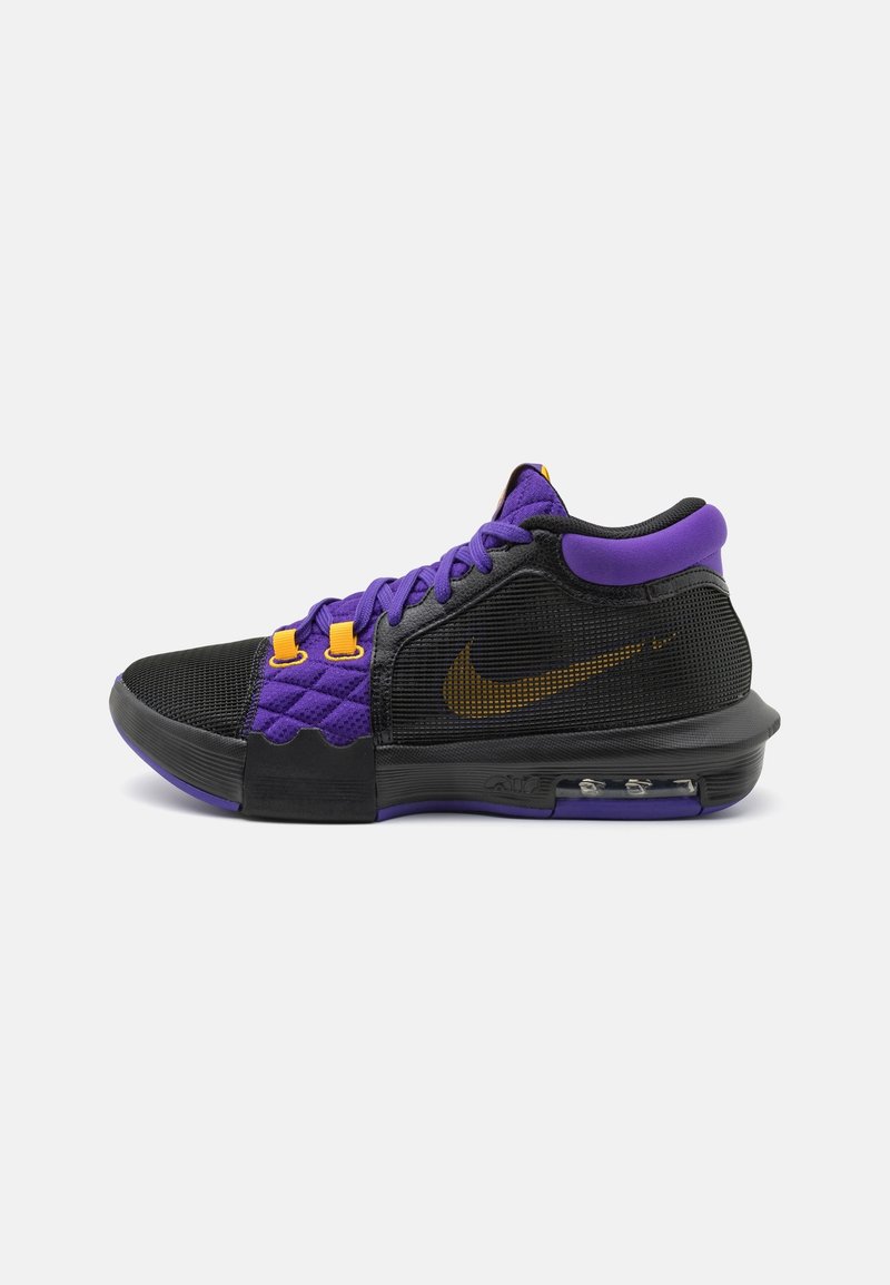 Des baskets Nike avec un dessus en maille noir et violet, des accents orange, un détail matelassé, et une unité d'air visible dans la semelle.