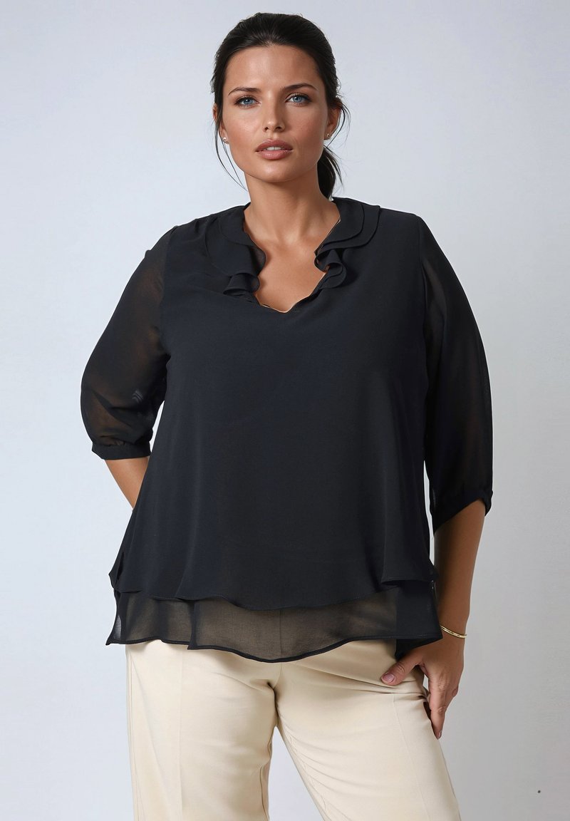 Zwarte, semi-doorzichtige blouse met een golvende halslijn en 3/4 mouwen, gelaagde ontwerp en een gladde textuur. Draagt over lichtgekleurde broeken.