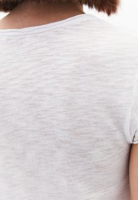 Witte, lichte t-shirt met een subtiele textuur, met een ronde halslijn en korte mouwen, gezien vanaf de achterkant.
