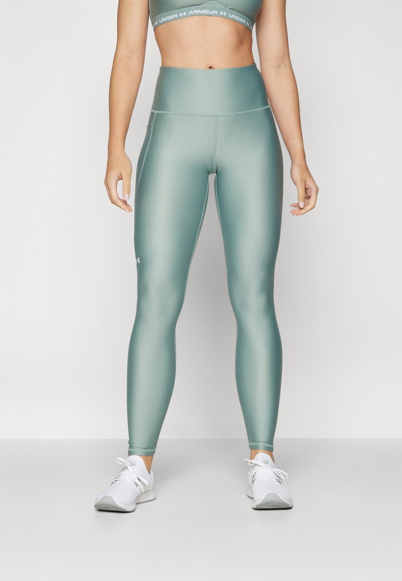 Leggings a vita alta di colore verde acqua realizzati in un tessuto liscio e elasticizzato; presentano un logo sulla coscia e si abbinano a un reggiseno sportivo coordinato.