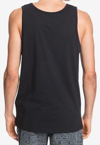 Svart bomullstopp med rund halsringning och utan ärmar. Har en enkel baksida och är kombinerad med mönstrade shorts.