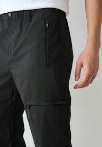 Schwarze, leichte Hose mit Reißverschlusstaschen, elastischem Bund und glatter Textur. Verfügt über maßgeschneiderte Nähte und eine moderne Passform.
