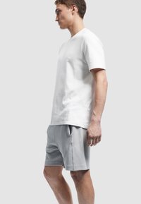 Hvid bomulds T-shirt med rund halsudskæring, parret med lysegrå shorts med sidelommer og en glat tekstur. Pænt, afslappet fit.