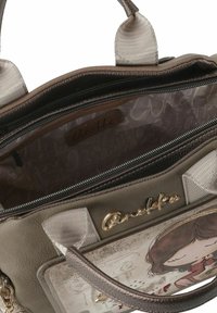 Beige Handtasche aus Kunstleder mit strukturierter Oberfläche. Verfügt über ein gemustertes Innenfutter, eine Reißverschlusstasche und Beschläge in Goldoptik.