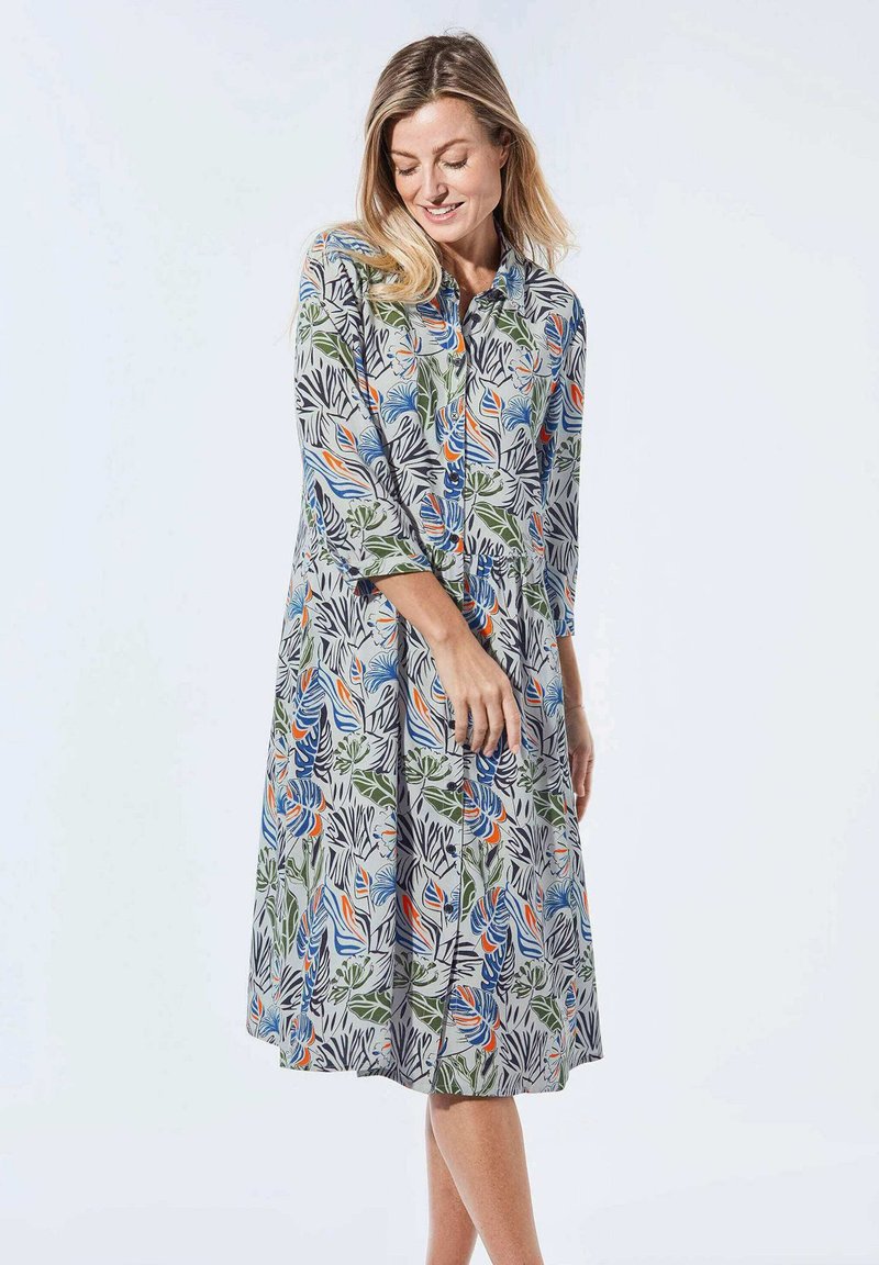 Blumenmusterkleid in Hellgrau mit grünen, blauen und orangefarbenen Blättern, Knöpfen an der Vorderseite und Dreiviertelärmel.