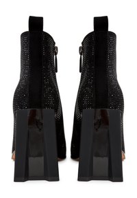 Botas negras hasta el tobillo con un upper texturizado que presenta rhinestones, un tacón negro liso y un discreto tirador en la parte posterior.